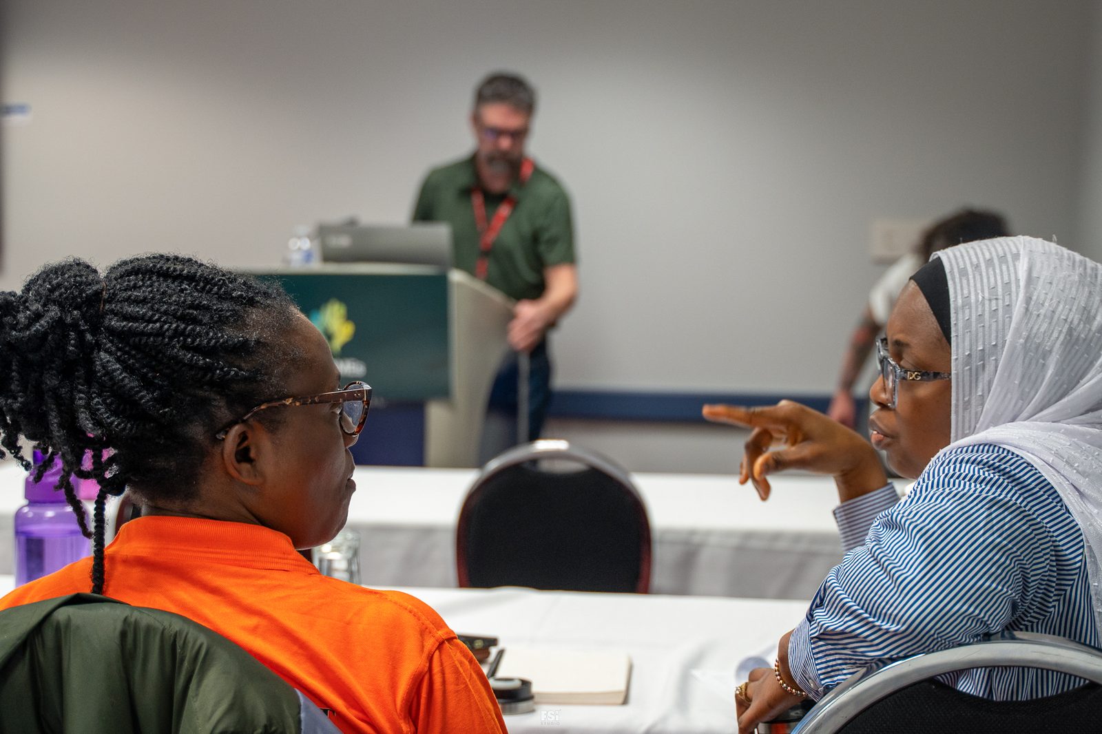 A facilitator presents at the CoBSMEs podium as Regina cohort participants listen