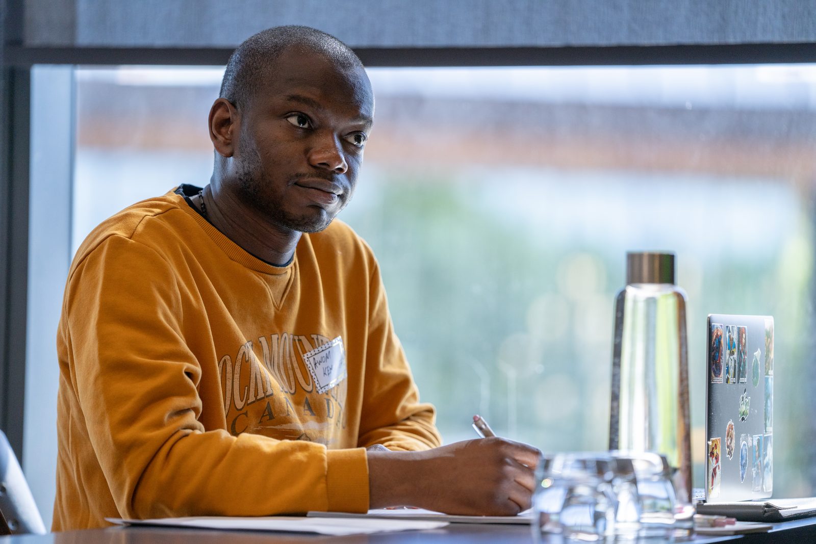 A participant takes notes by the window during a Saskatoon session